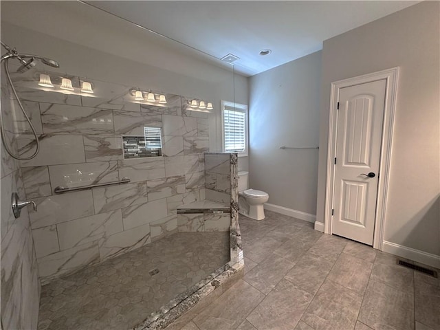 bathroom featuring a tile shower and toilet