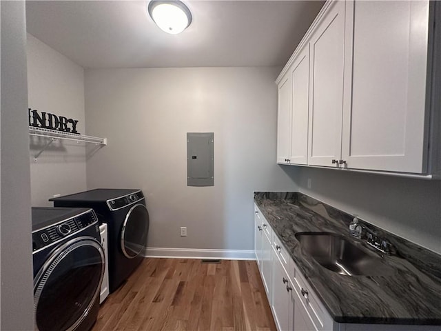 laundry area with sink, cabinets, light hardwood / wood-style flooring, electric panel, and washer and dryer