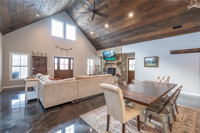 dining area with high vaulted ceiling, ceiling fan, a stone fireplace, and wood ceiling