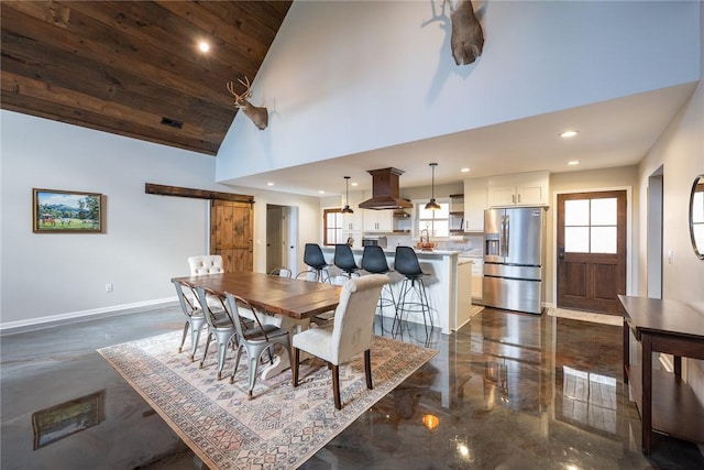 dining room with a barn door, wood ceiling, and high vaulted ceiling