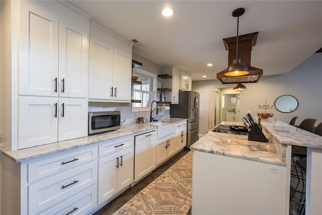 kitchen with a breakfast bar, white cabinetry, stainless steel appliances, and decorative light fixtures