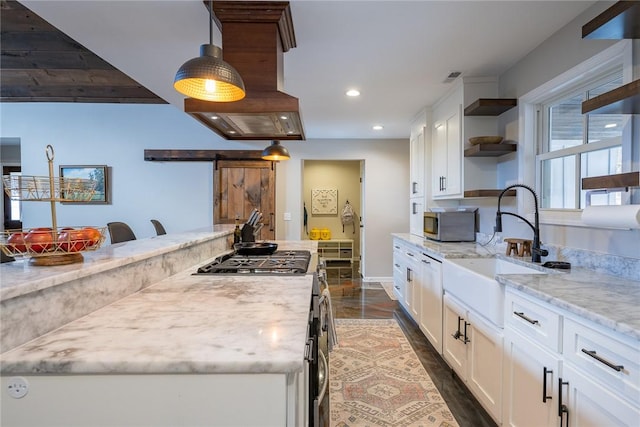 kitchen featuring light stone countertops, a barn door, white range with gas stovetop, and white cabinetry