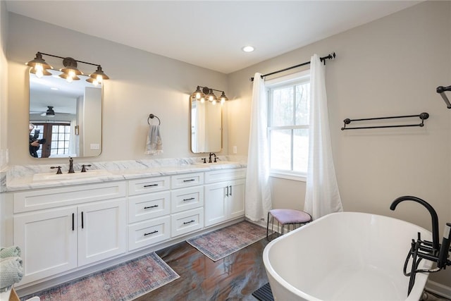 bathroom with ceiling fan, a washtub, vanity, and wood-type flooring