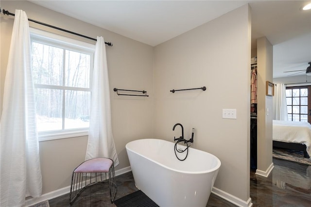 bathroom featuring a tub to relax in, ceiling fan, and a healthy amount of sunlight