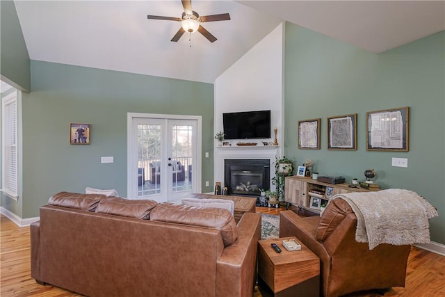 living room with ceiling fan, light hardwood / wood-style flooring, high vaulted ceiling, and french doors