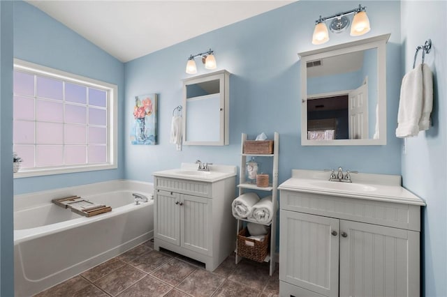 bathroom featuring a bathing tub, vanity, tile patterned floors, and lofted ceiling