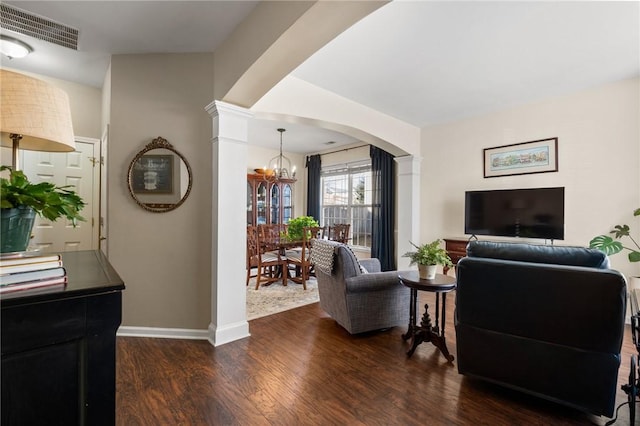 living room with decorative columns, dark hardwood / wood-style flooring, and a chandelier