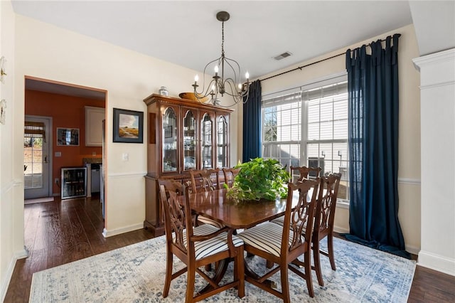 dining area featuring dark wood-type flooring, beverage cooler, and an inviting chandelier