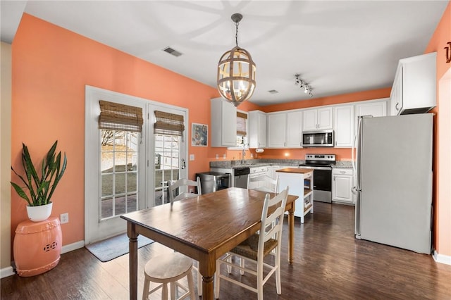 dining space featuring an inviting chandelier, dark wood-type flooring, and sink