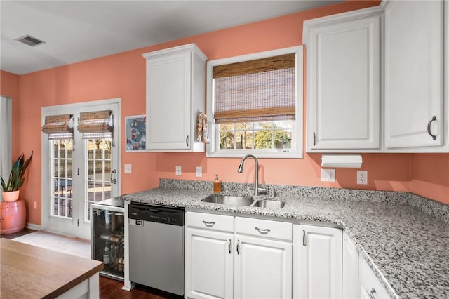 kitchen with light stone countertops, sink, white cabinets, and stainless steel dishwasher