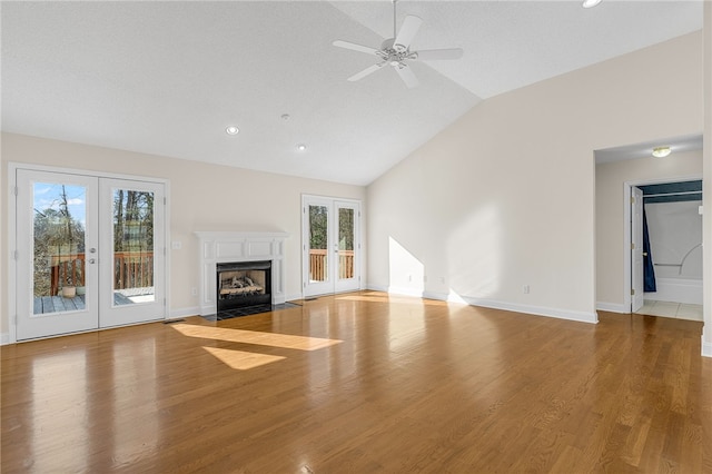 unfurnished living room with ceiling fan, french doors, lofted ceiling, and light wood-type flooring