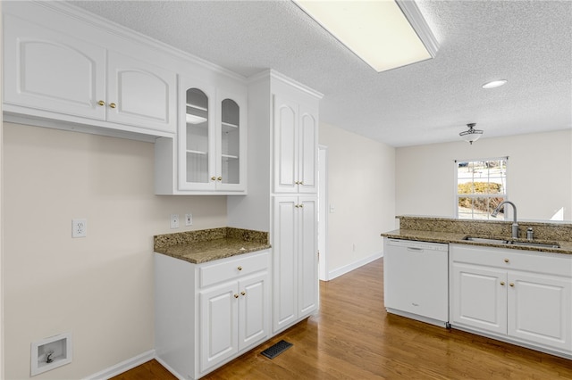 kitchen with white cabinetry, dishwasher, dark stone counters, and sink