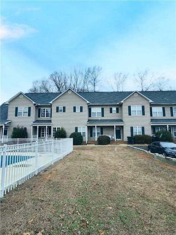 rear view of property with a covered pool and a lawn