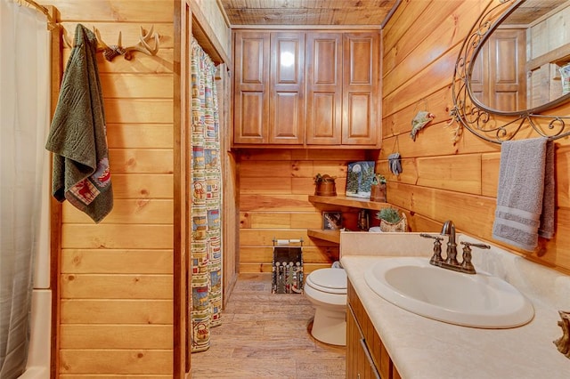 bathroom featuring toilet, vanity, wooden walls, and wood-type flooring