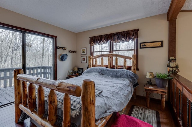 bedroom featuring access to exterior, dark hardwood / wood-style flooring, and a textured ceiling