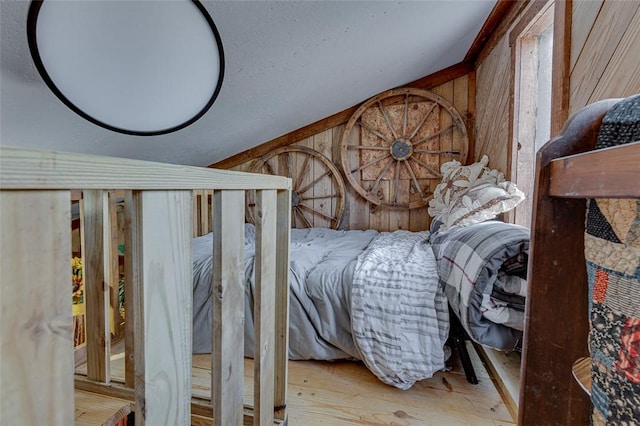 bedroom with light wood-type flooring and wooden walls