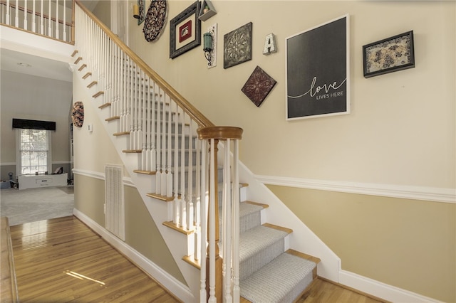 stairs featuring a towering ceiling and hardwood / wood-style floors