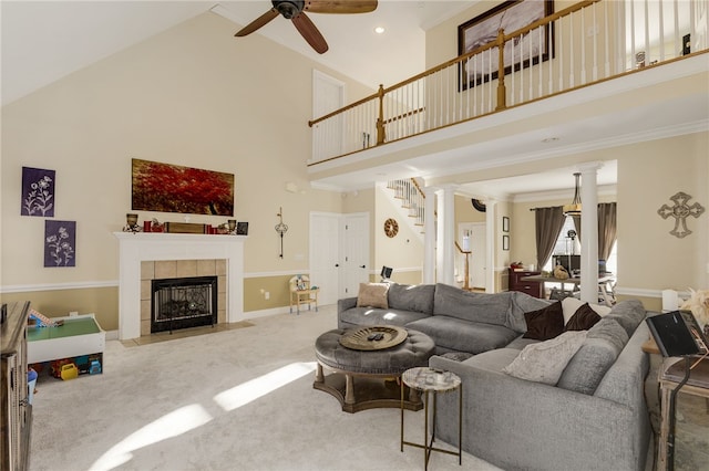 carpeted living room with high vaulted ceiling, a tiled fireplace, crown molding, and ceiling fan