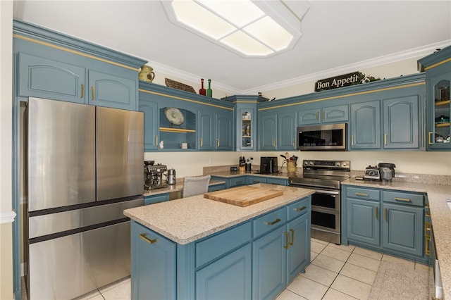 kitchen with light tile patterned floors, blue cabinetry, appliances with stainless steel finishes, and crown molding