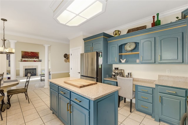 kitchen featuring a tile fireplace, hanging light fixtures, blue cabinets, ornamental molding, and stainless steel fridge