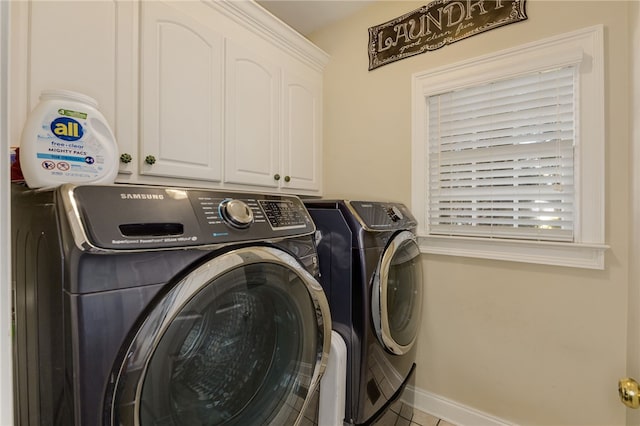 clothes washing area featuring cabinets, light tile patterned floors, and washer and clothes dryer