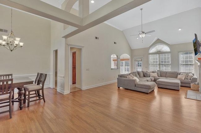 living room featuring a wealth of natural light, ceiling fan with notable chandelier, and a high ceiling