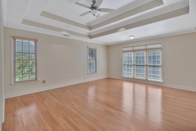 unfurnished room with ceiling fan, a raised ceiling, ornamental molding, and light hardwood / wood-style flooring