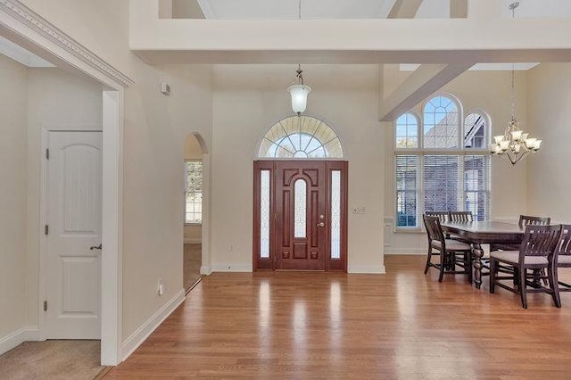 foyer entrance with a wealth of natural light, hardwood / wood-style floors, a high ceiling, and an inviting chandelier