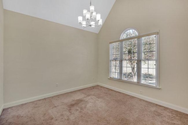 carpeted spare room featuring plenty of natural light, high vaulted ceiling, and an inviting chandelier