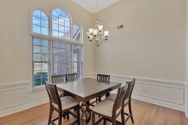 dining space with a chandelier, light wood-type flooring, and ornamental molding