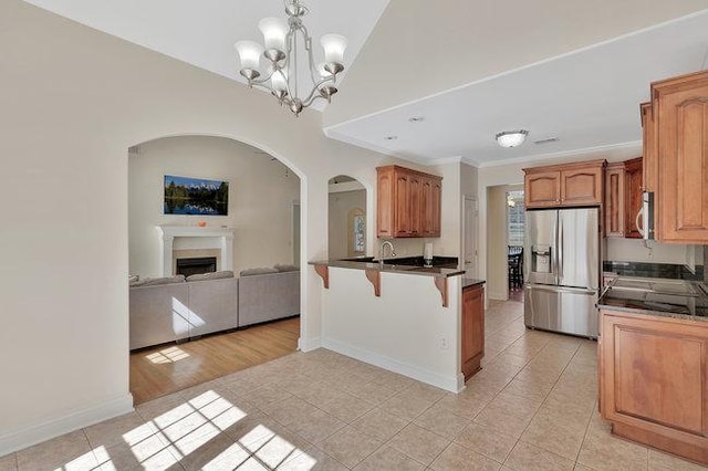 kitchen featuring hanging light fixtures, stainless steel appliances, an inviting chandelier, kitchen peninsula, and a kitchen bar