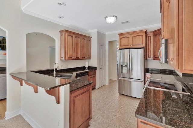 kitchen featuring kitchen peninsula, stainless steel appliances, crown molding, sink, and dark stone countertops