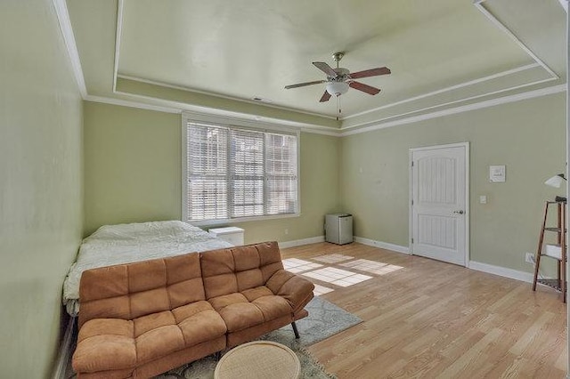 bedroom featuring a tray ceiling, light hardwood / wood-style flooring, ceiling fan, and ornamental molding