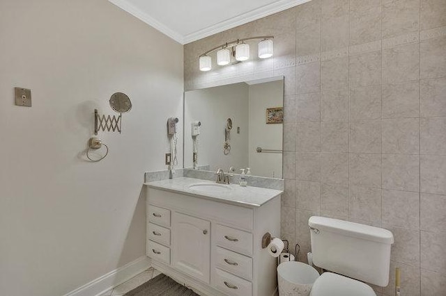 bathroom featuring vanity, tile patterned floors, toilet, ornamental molding, and tile walls