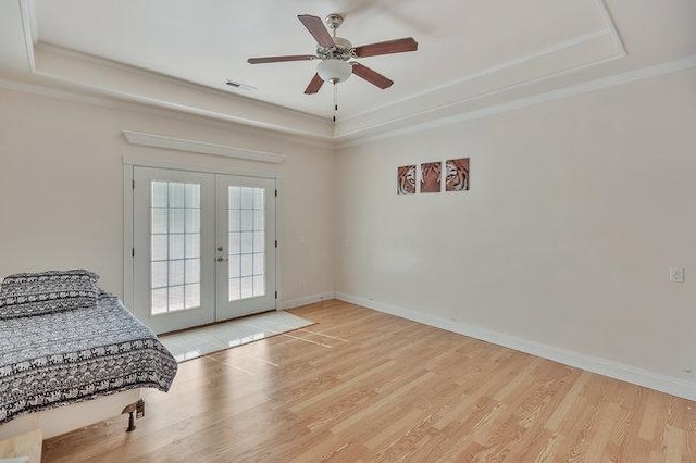 bedroom featuring access to exterior, french doors, light wood-type flooring, a tray ceiling, and ceiling fan