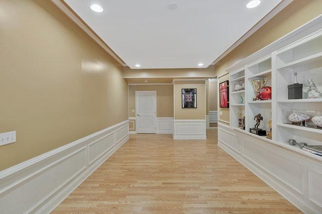 hallway featuring built in shelves, light hardwood / wood-style floors, and ornamental molding