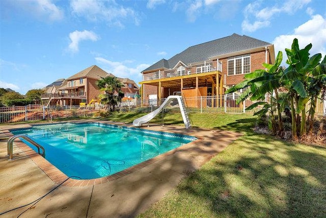 view of pool featuring a lawn, a patio area, and a water slide