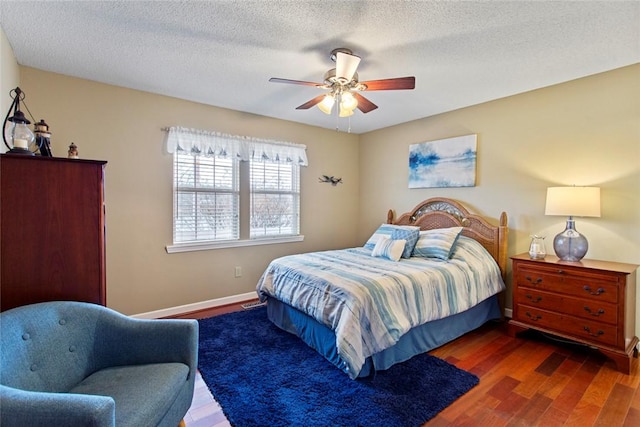 bedroom with a ceiling fan, a textured ceiling, baseboards, and wood finished floors