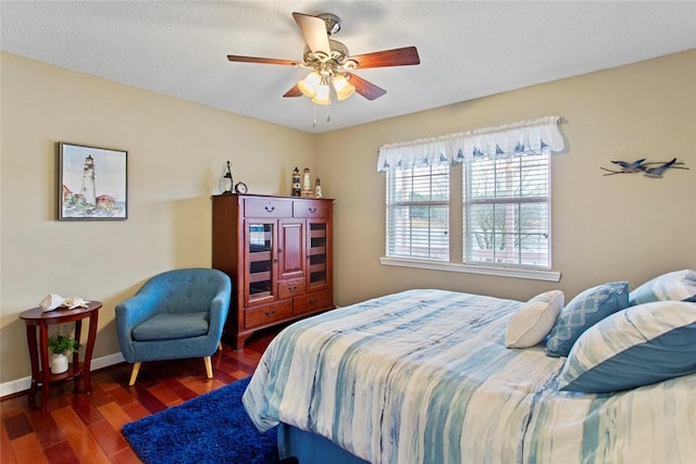 bedroom featuring ceiling fan, a textured ceiling, baseboards, and wood finished floors