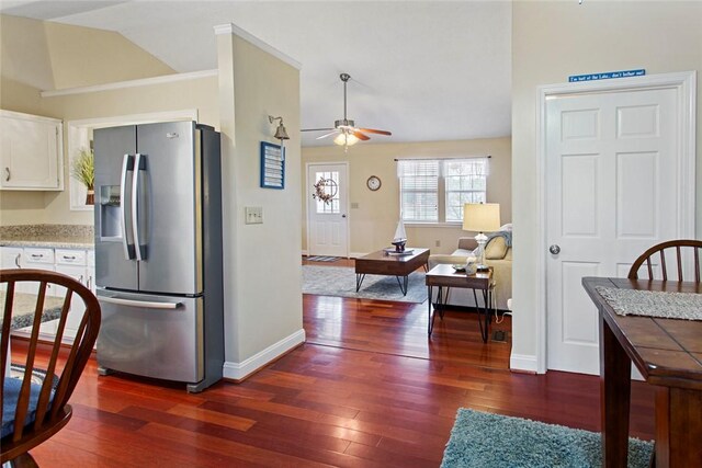 kitchen with dark wood-type flooring, white cabinets, vaulted ceiling, ceiling fan, and stainless steel fridge