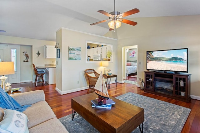 living area with vaulted ceiling, ceiling fan, wood finished floors, and baseboards