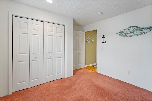 unfurnished bedroom with a closet, light carpet, and a textured ceiling