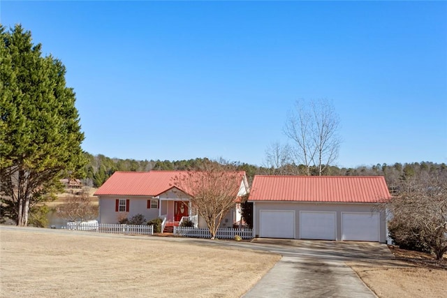 view of front of house with driveway, a fenced front yard, a garage, and metal roof