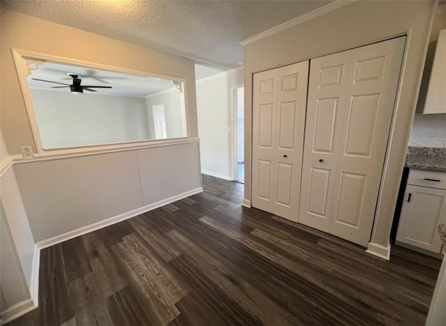 interior space featuring ornamental molding, a textured ceiling, ceiling fan, dark hardwood / wood-style floors, and a closet