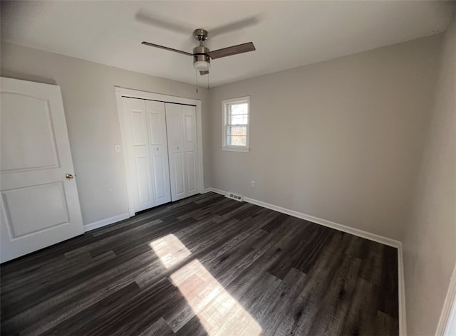 unfurnished bedroom featuring dark hardwood / wood-style flooring, ceiling fan, and a closet