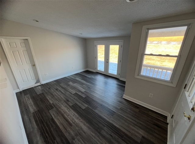 empty room featuring dark hardwood / wood-style floors, a textured ceiling, and french doors