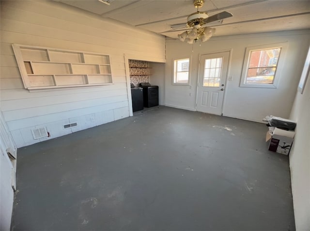 interior space featuring ceiling fan and wood walls