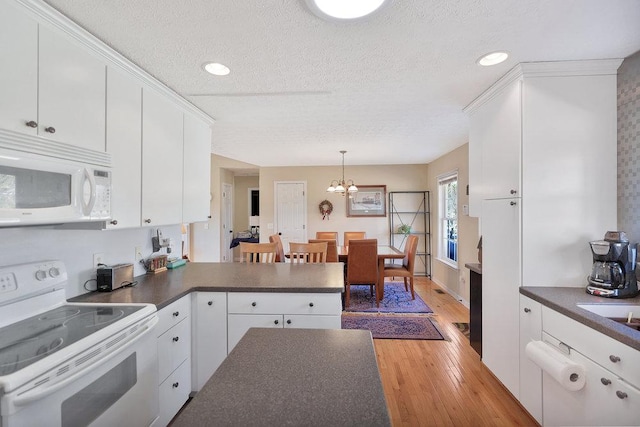 kitchen with dark countertops, white appliances, and white cabinetry