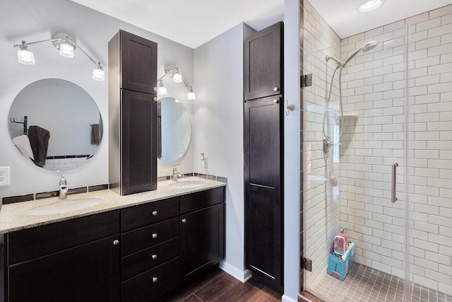 bathroom featuring double vanity, a stall shower, and a sink