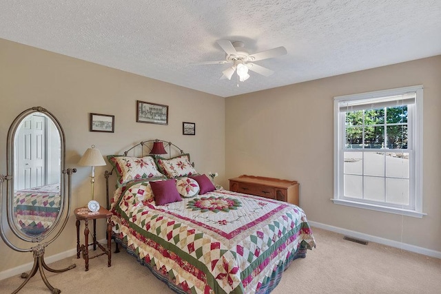 carpeted bedroom with visible vents, baseboards, a textured ceiling, and a ceiling fan